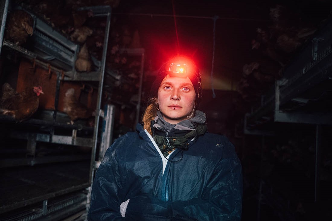 Recherche-Aktivistin Anna blickt in die Kamera. Sie trägt eine rote Stirnlampe und einen blauen Overall