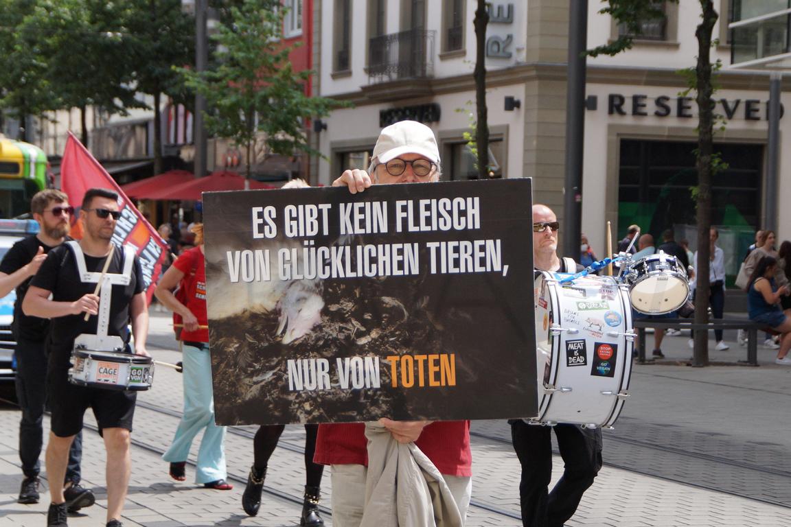 Demonstrationsteilnehmer hält ein Schild hoch, auf dem eine tote Pute zu sehen ist und der Spruch "Es gibt kein Fleisch von glücklichen Tieren, nur von toten"