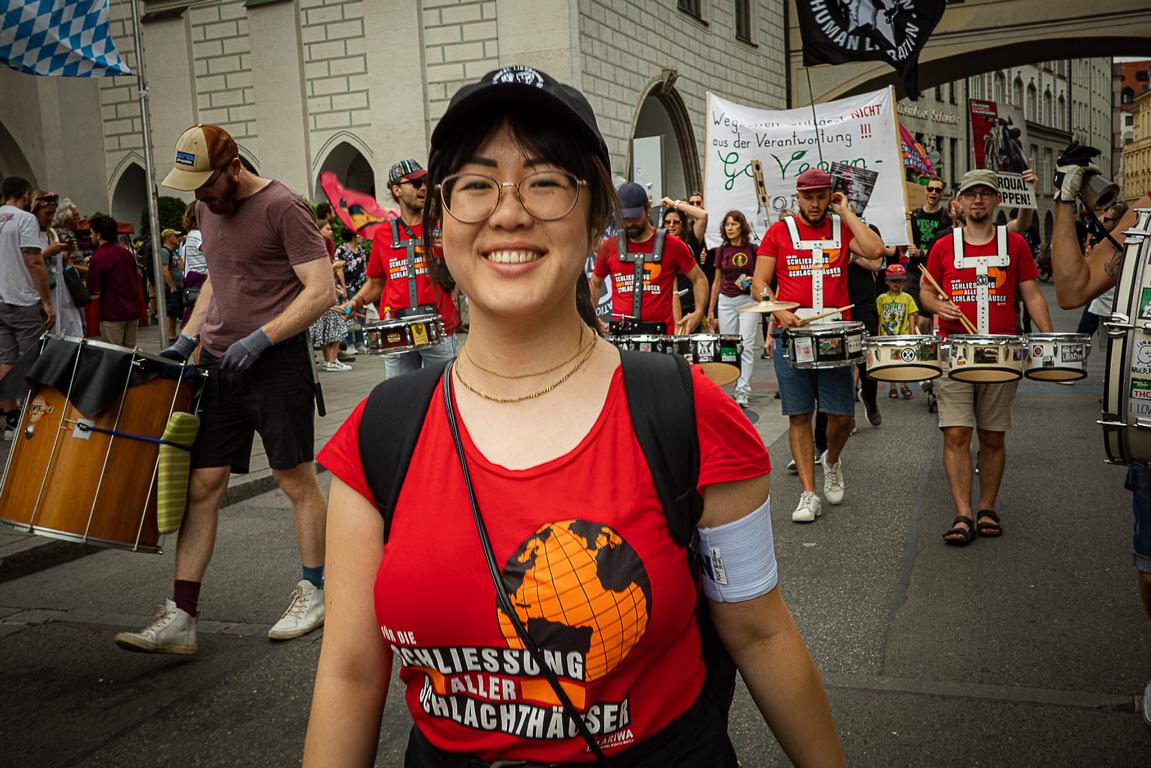 Eine Frau mit "Schlachthäuser Schließen" T-Shirt lacht in die Kamera auf einer Demonstration